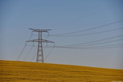 Low angle view of electricity pylon on field against sky