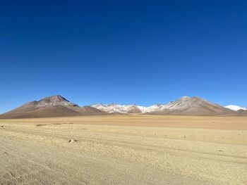 Scenic view of arid landscape against clear blue sky