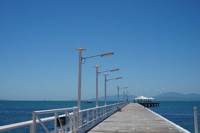 Pier over sea against clear blue sky