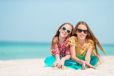 Portrait of sisters sitting on beach