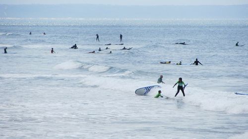 Surfers in sea on sunny day
