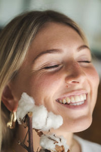 Portrait of the woman holding cotton flower next to her face smiling
