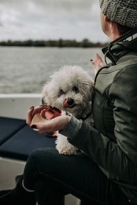 Woman with dog sitting in boat on sea against sky