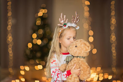 Cute girl kissing stuffed toy at home