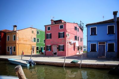 Boats moored in canal against clear blue sky