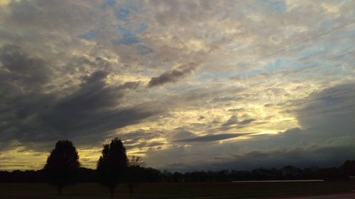 Silhouette trees on field against sky at sunset