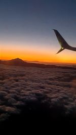 Airplane flying in sky at sunset