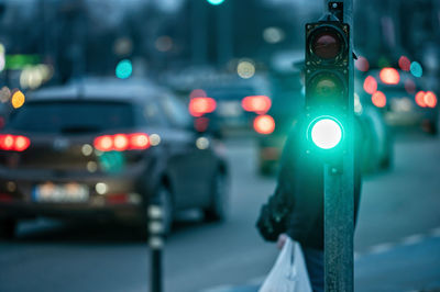 A city crossing with a semaphore on blurred background with cars in the evening streets, green light