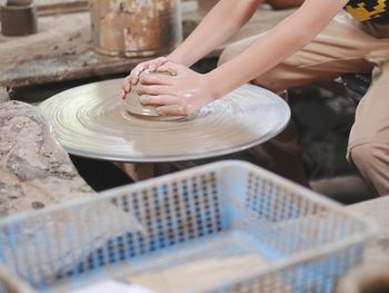 Midsection of person making pot on pottery wheel