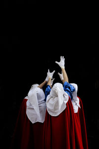 Rear view of friends standing against black background