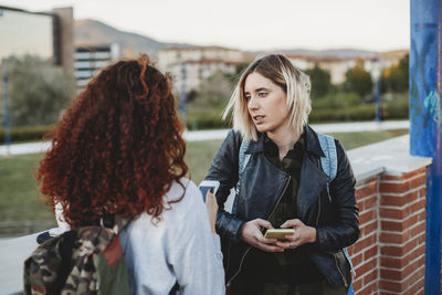 Two young student using smartphone at the park together