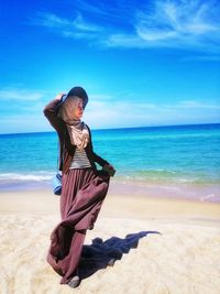 Young woman at beach against sky