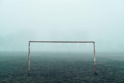 A football goalpost sits in a foggy park.