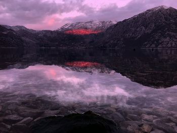 Scenic view of lake by mountains against sky at sunset