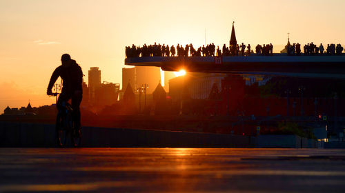 Silhouette of people at illuminated city during sunset