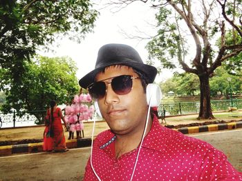 Portrait of young man wearing sunglasses against trees