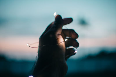 Close-up of hand holding illuminated string light