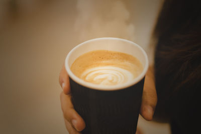 Close-up of hand holding coffee cup