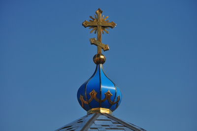 Low angle view of cross sculpture against clear blue sky