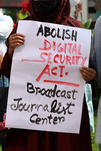 Text on man holding camera sign