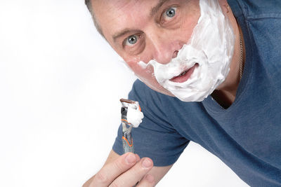 Close-up portrait of man holding hands over white background