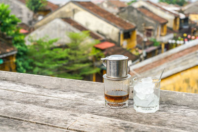 Close-up of glass bottle on table against building