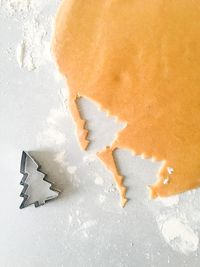 Directly above shot of christmas tree pastry cutter with dough on table