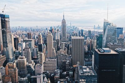 Aerial view of buildings in city against cloudy sky