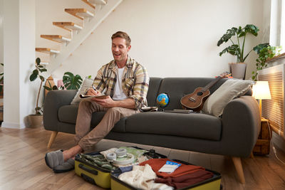 Young man using phone while sitting on sofa at home