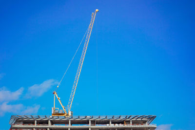 Low angle view of crane against blue sky. hospital construction
