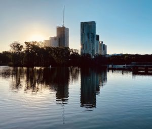 Reflection of buildings in lake against sky in city