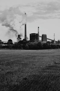 Smoke emitting from factory against sky