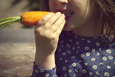Midsection of girl eating carrot