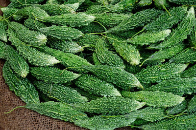 High angle view of bitter gourds on jute for sale at market stall