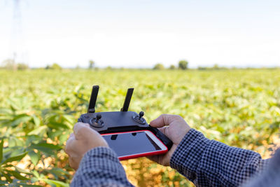 Midsection of man using mobile phone in field