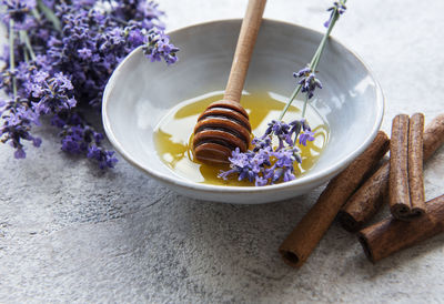 Bowl with honey and fresh lavender flowers on a concrete background