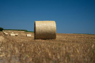 Hay bales on field against clear sky