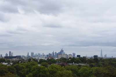 Buildings in city against cloudy sky