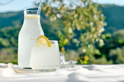 Summer refreshing lemonade drink or alcoholic cocktail with ice, rosemary and lemon slices on table