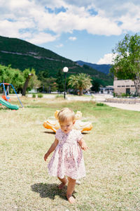 Girl with arms raised on field against sky