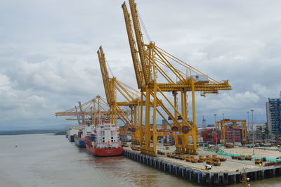 Cranes at pier against sky