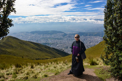 Full length portrait of woman standing on mountain against sky