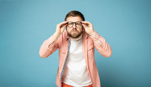 Young man standing against blue background