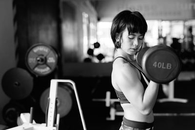 Side view of young woman exercising at gym