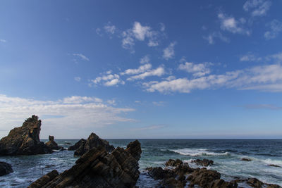 Rock formation on beach against sky