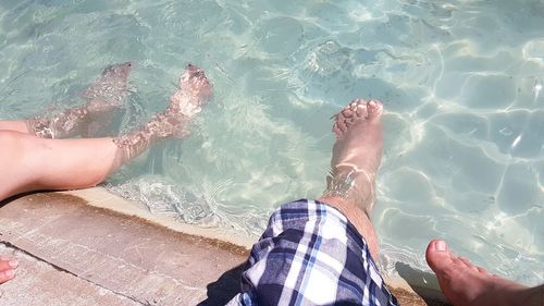 Low section of people sitting with feet in sea