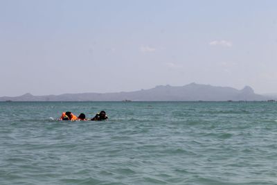 People in boat on sea against sky