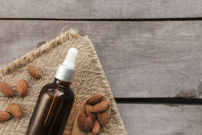 Almond essential oil in glass bottle with spoon. cosmetic concept on wooden background