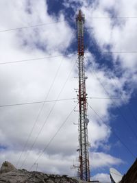 Low angle view of electricity pylon against cloudy sky