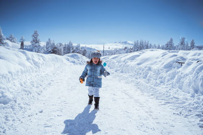 Full length of woman skiing on snow covered field against sky